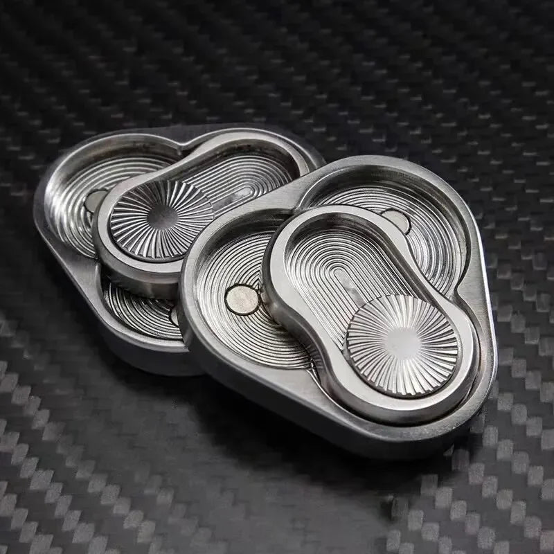 Stainless steel fidget spinner with intricate engraved patterns on a carbon fiber surface