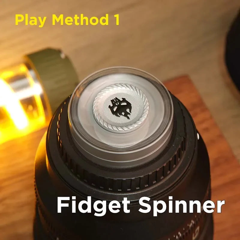 Close-up of a metal fidget spinner on a tabletop, labeled 'Play Method 1'.